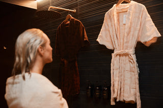 The ecru SENA cotton robe hanging in a sauna change room