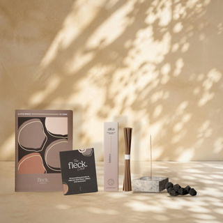 The Reset bundle: the Fleck Journal, the Fleck Deck, Balance incense and a marble incense holder with lava stones against a leaf shadow wall