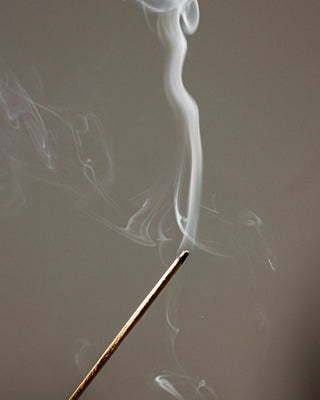 A lit incense stick with a thin thread of smoke