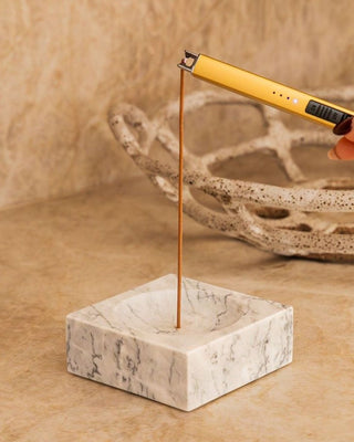 Lighting an incense stick standing in the marble holder