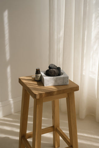 The marble holder with lava stones on a small timber stool by a window