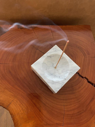 The marble incense holder on a timber block with smoke rising