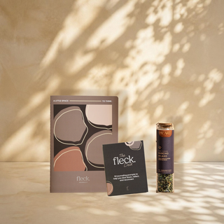 The Five Minute Breather bundle: the Fleck Journal, the Fleck Deck and a jar of Rancho Relaxo tea against a leaf shadow wall
