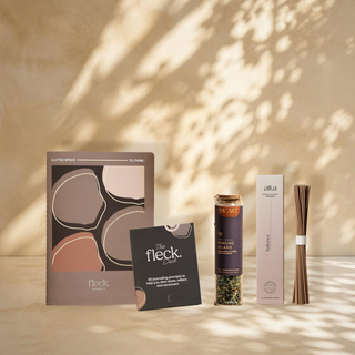 The Wind Down bundle: the Fleck Journal, the Fleck Deck, Rancho Relaxo tea and Balance incense against a leaf shadow wall